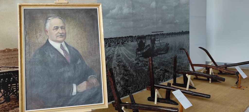 Z lewej strony portret profesora Stefana Biedrzyckiego. W tle jego kolekcja drewnianych narzędzi rolniczych.ane.
