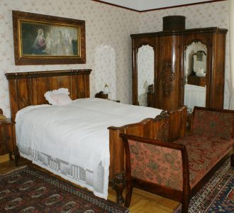stara sypialnia z drewnianym łóżkiem, szafą i obrazem nad łóżkiem